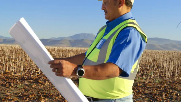 Male engineer holding blueprint in the field on a sunny day 4k