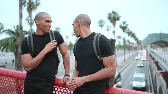 Two positive bald African brothers talking on the bridge