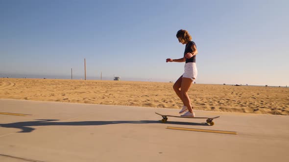Sporty Young Woman In Casual Wear Skateboarding On A Sunny Desert Park. Slow Motion, Tracking Shot