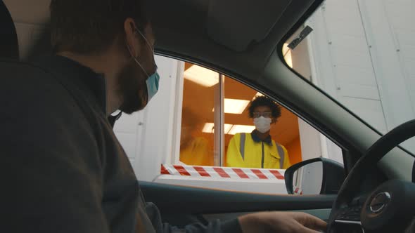 Man Driver in Safety Mask Stopping Near Security Booth for Temperature Scanning Before Entering Area