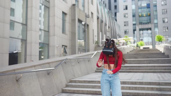 Woman in a Virtual Reality Helmet Walks Down the Street