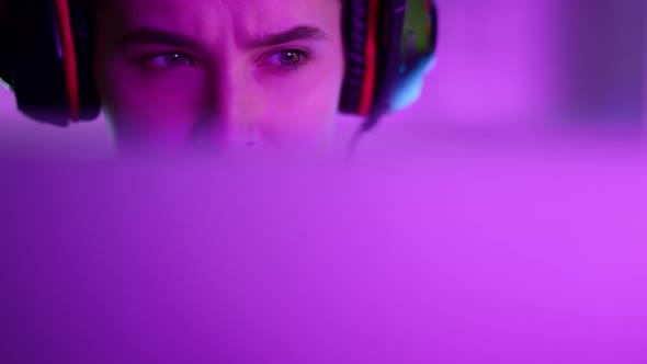 Beautiful Neon Gamer Playing Computer Game in Pink Neon Lights at Home Closeup