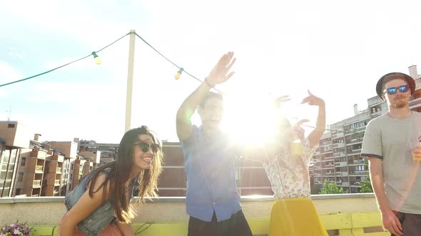 Four cheerful friends dancing on the rooftop terrace