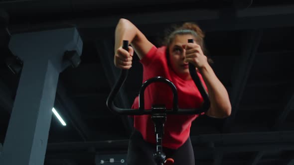 Woman Performs Aerobic Endurance Training Workout Cardio Routine on the Simulators Cycle Training
