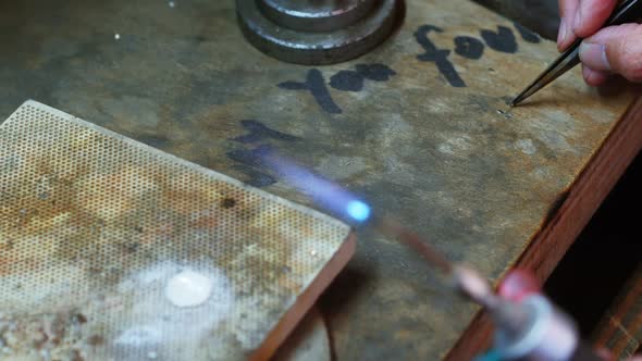 Close-up of Craftswoman blowing a torch to melt metal