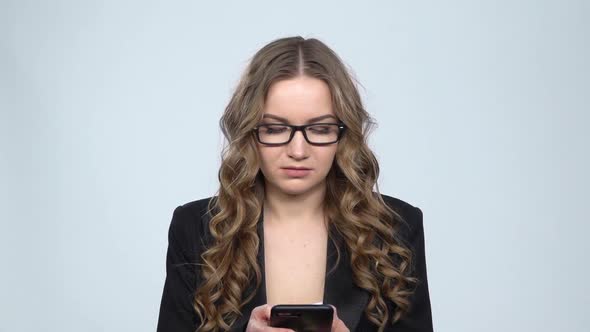 Angry Businesswoman Texting on Her Phone on Gray Background in Studio, Slow Motion