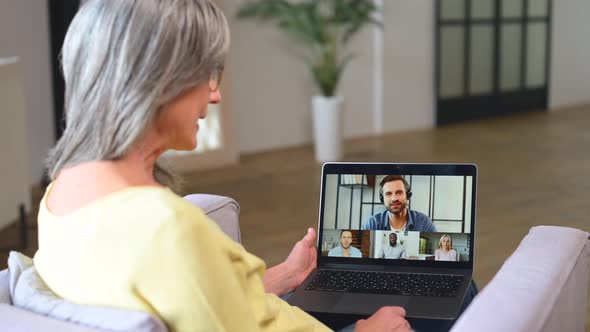 Contemporary Senior Woman Sitting on Armchair and Using Laptop for Video Connection