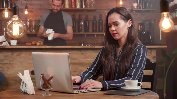Young Creative Woman Closes Her Laptop and Leaving the Table of a Small Coffee Shop