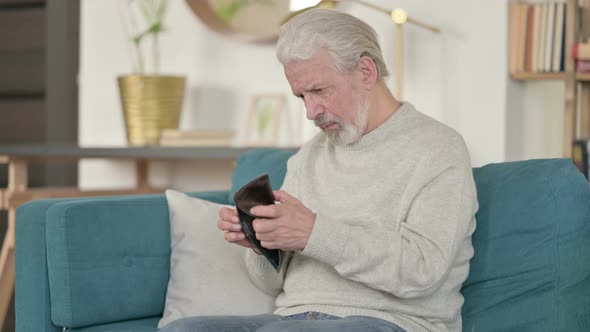 Broke Old Man Checking Empty Wallet on Sofa 