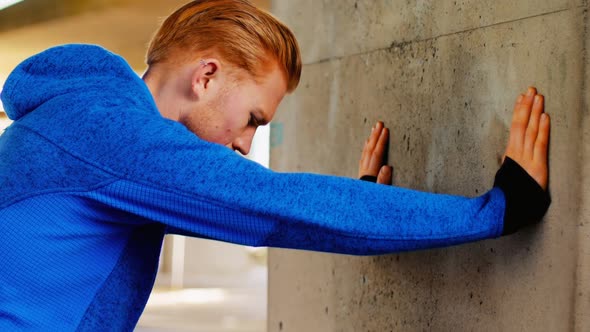 Young man pushing against wall while exercising, 4K 4k