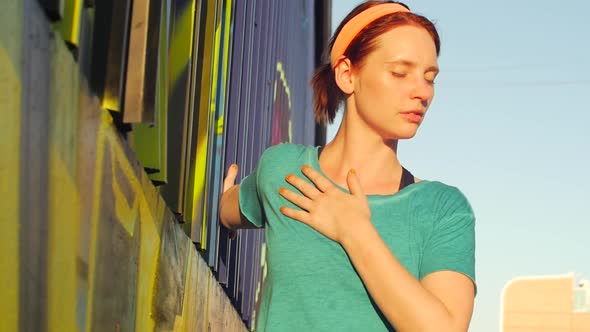 A young woman stretching before working out in urban environment.