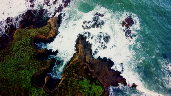 Waves crash into rocky coves eroded out of tall cliffs in California