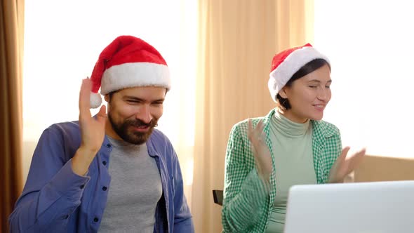 Loving Multiracial Couple Man and Woman in Santa Hats are Smiling and Hugging Talking By Online