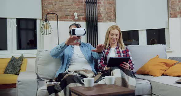 Couple which Resting on Soft couch in Living-Room and Using Virtual Reality Headset