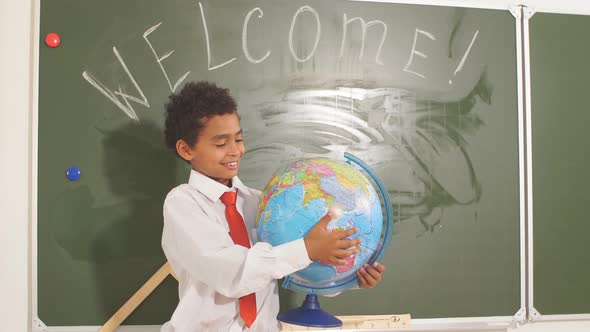 African American Boy with Globe on Study Table on Chalk Board Background