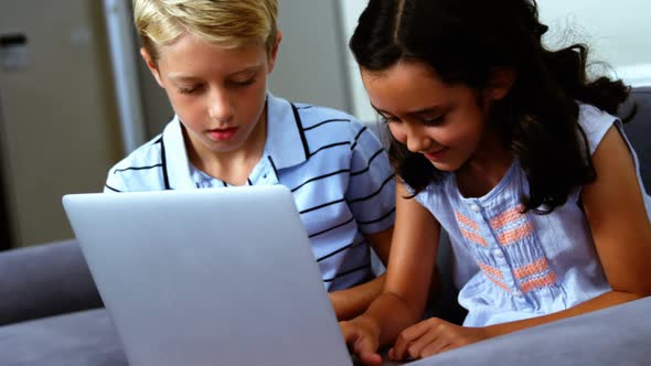 Siblings using laptop in living room