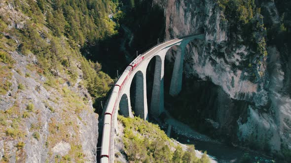 Aerial View of a Moving Red Train Along the Landwasser Viaduct in Swiss Alps