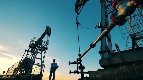 Oil Worker Inspecting Two Crude Oil Pump Jacks