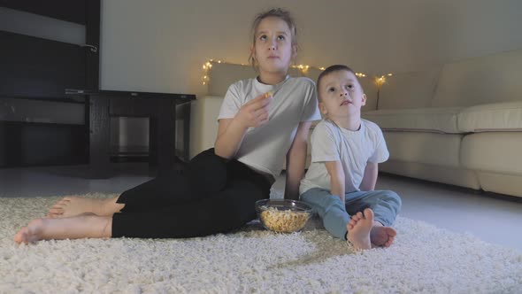 Happy Family Brother and Sister Watching Tv with Popcorn Bowl at Home