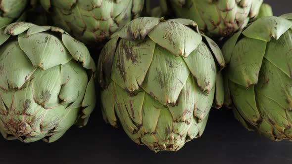 Whole Fresh Artichokes on Black Table