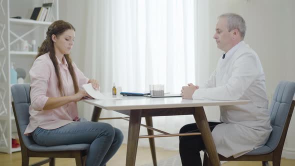 Mid-adult Doctor Refusing To Take Bribe From Woman in Hospital. Side View Portrait of Professional