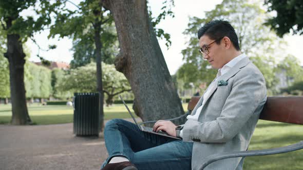 Korean Businessman Using Laptop In Park