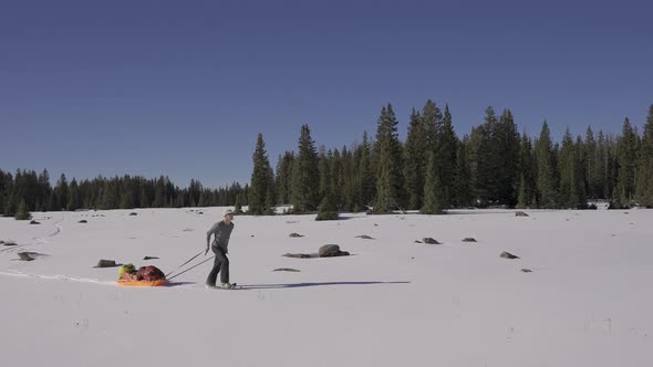 Man in nature with snowshoes and his sled exploring the wild.