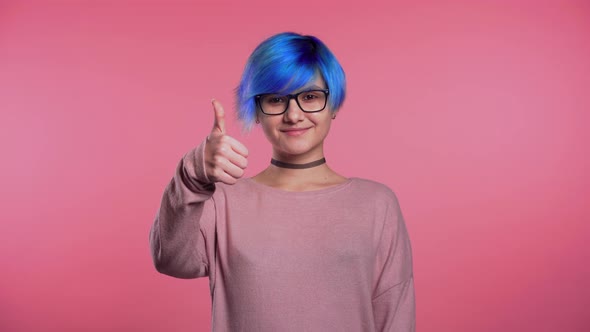 Young Punk Unusual Woman Blue Hair Making Thumbs Up Sign Over Pink Background