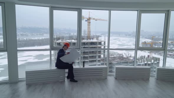 Man Looking on the Construction Site Through the Window