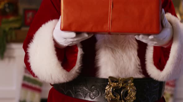 Santa Claus peeks out from behind stack of gifts