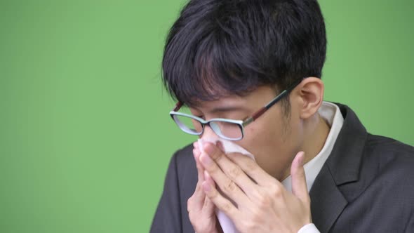 Sick Young Asian Businessman Blowing Nose on Tissue