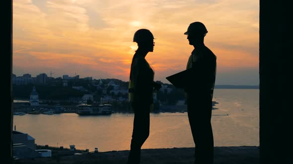 Two Builders Working on a Sunset Background