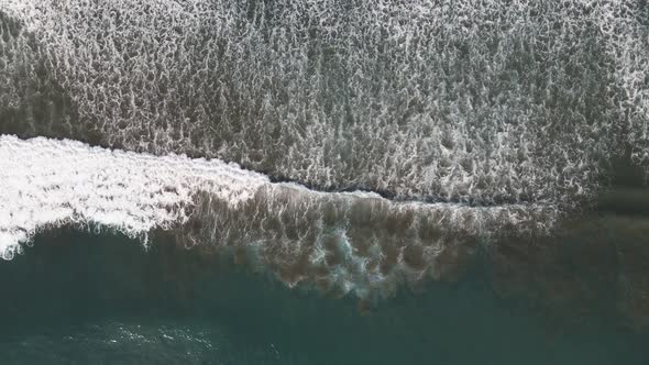 Aerial view of waves crashing upon shore in Dominical Beach in Costa Rica, bird eye wide shot