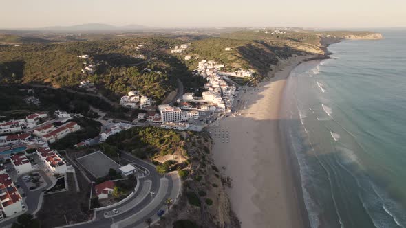 Panning aerial view of coastal village Praia da Salema beach in Algarve Portugal.