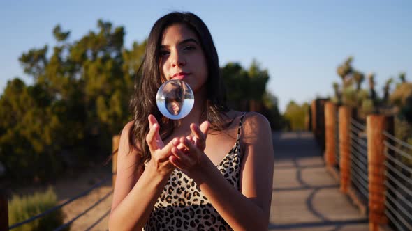 A beautiful hispanic model playing with a magical crystal ball in slow motion while smiling and laug