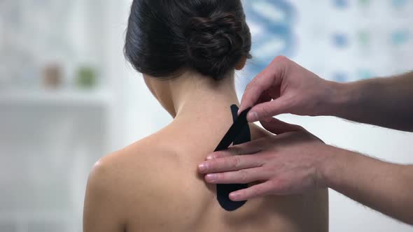 Doctor Applying Y-Shaped Tapes on Patient Upper Back, Alternative Medicine