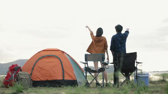 Young Asian couple campers trekking in mountains park celebrating successful.