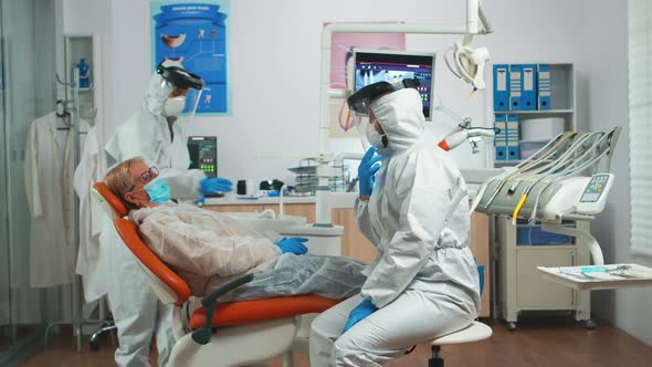 Woman Explaining Dental Problem to Doctor Wearing Protection Suit