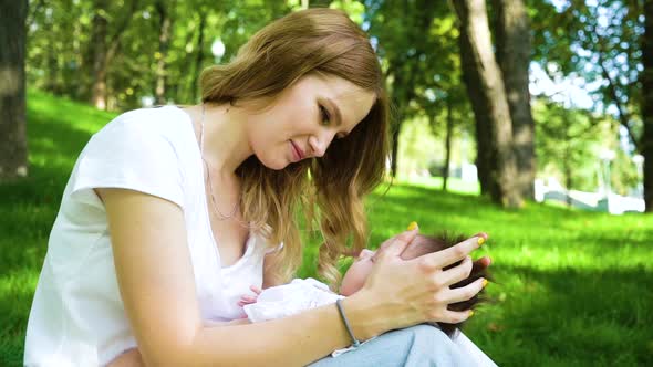 Beautiful young mother with sleeping baby in park