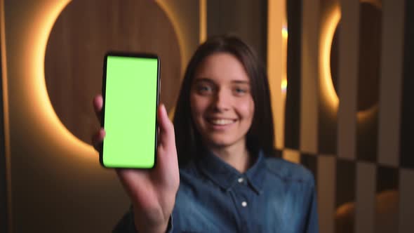 Portrait of Pretty Smiling Caucasian Businesswoman Showing Smartphone with Green Screen Chromakey at