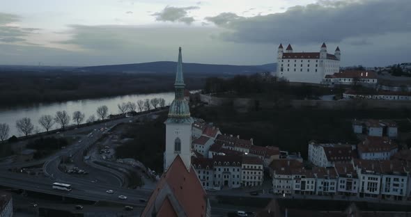 Flying backwards from St. Martin Church in Bratislava at twilight with Castle in background, Aerial