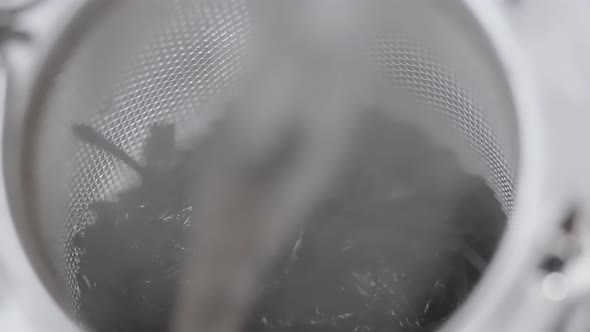 brewing fragrant dried green tea leaves in a glass teapot. tea leaves close-up.