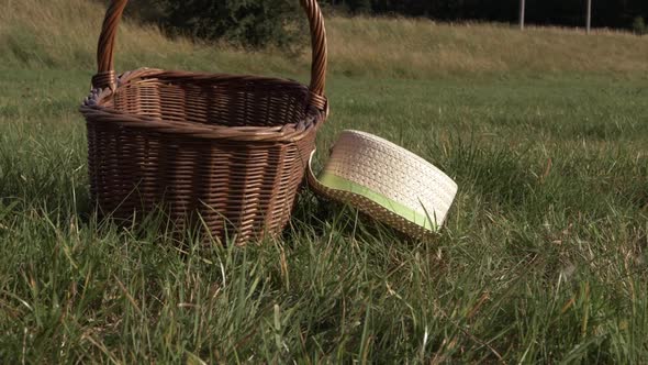 Straw hat and woven basket in a field medium panning shot