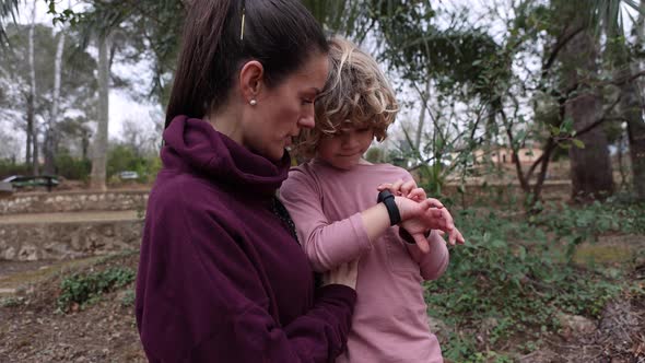 Mom explaining to son how to use wristwatch outdoors