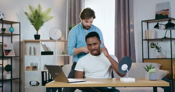 Barber Making Stylish Hairdo Using Trimmer for His Male African American Client on Home