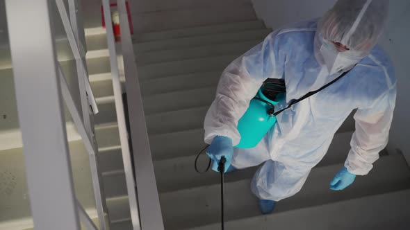 Worker Spraying Disinfectant on Staircase Landing of the House