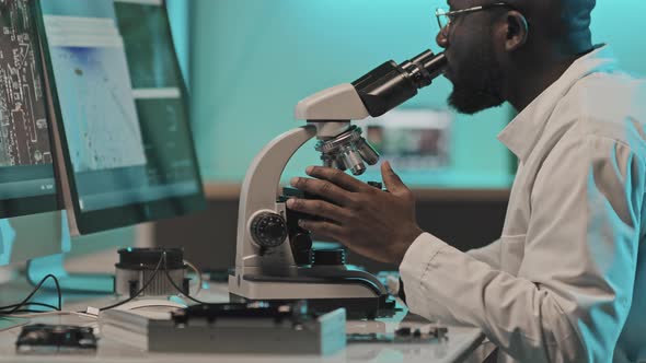 Engineer Using Microscope for Examining Electronics in Lab