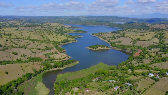 Aerial flyover Bao River surrounded by green hilly landscape during sunlight - Dominican Republic at