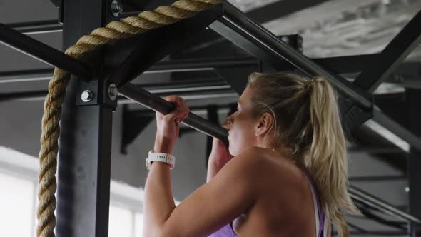 Side view athletic Caucasian woman doing chin ups