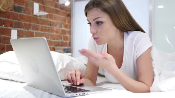 Online Video Chat on Laptop By Woman Lying in Bed at Night